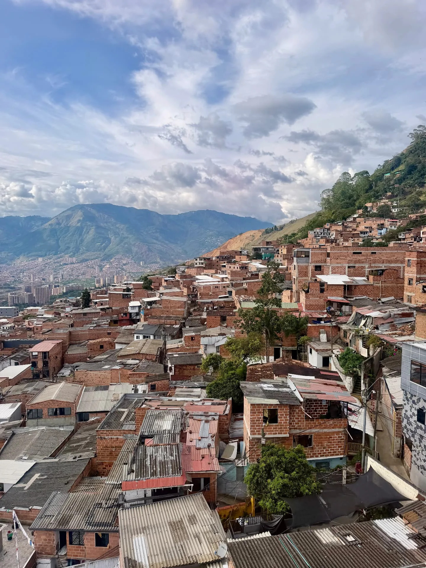 Hillside neighbourhood of Medellín with brick houses and mountains in the distance